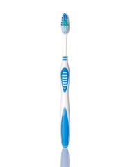 A close-up, high-angle shot of a toothbrush. It's white with a blue handle and bristles, and cast in the center of a white reflective surface