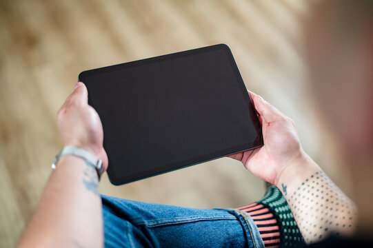 A man in his 30s, wearing a smartwatch, sits comfortably and interacts with a tablet at home - Powered by Adobe