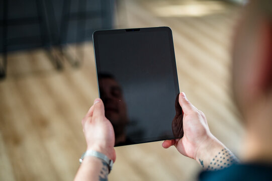 A man in his 30s uses a tablet at home, highlighting tech and lifestyle