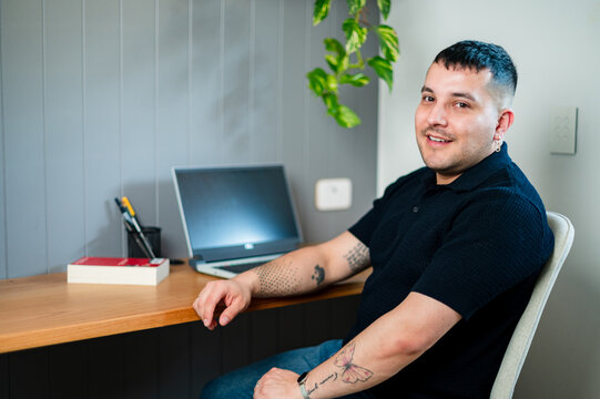 A man in his 30s, working from a comfortable home office with a laptop