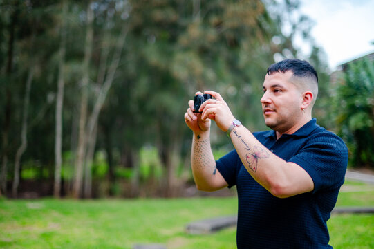 A man in his 30s is taking pictures in a park, enjoying outdoor photography and leisure time