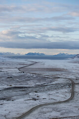 Longyerbeyen, Svalbard, Snowy landscape with a road running through it. The sky is cloudy and the mountains in the background are covered in snow