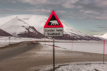 Longyerbeyen, Svalbard, Sign with a polar bear on it is posted on a road in a snowy landscape