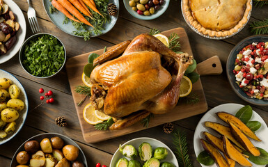 Overhead shot of a festive thanksgiving or christmas dinner spread with roasted turkey, sides, and desserts on a rustic wooden table, ready for a holiday feast christmas