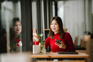 A woman wearing headphones works on a tablet in a cozy café, focused and relaxed by the window.