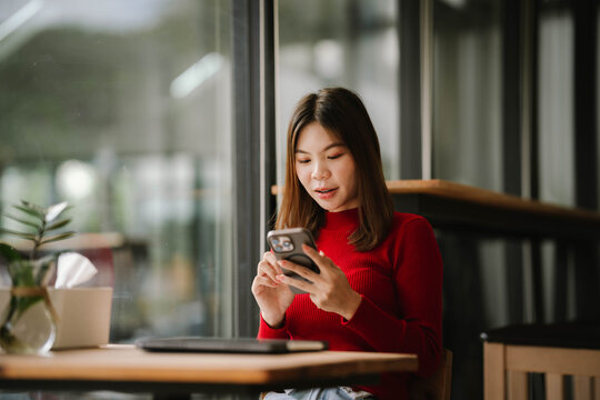 A woman wearing headphones works on a tablet in a cozy café, focused and relaxed by the window. - Powered by Adobe