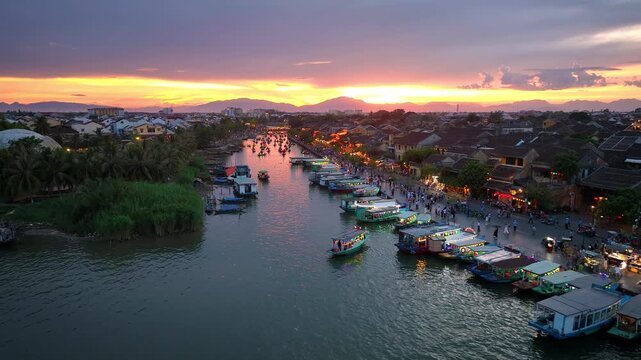 Aerial view of Hoi An ancient town along the Thu Bon River in Vietnam. Tourists ride long-tail boats decorated with lanterns, a popular nightlife destination in Quang Nam Province, Vietnam.