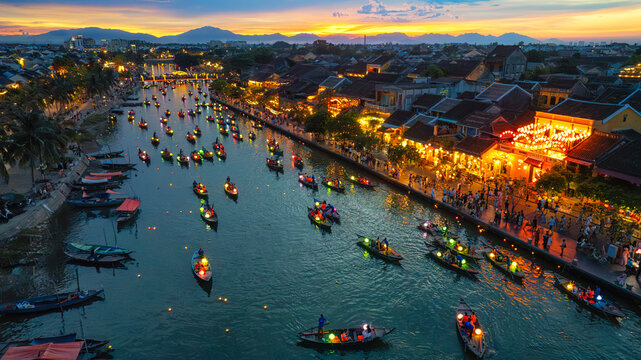 Aerial view of Hoi An ancient town along the Thu Bon River in Vietnam. Tourists ride long-tail boats decorated with lanterns, a popular nightlife destination in Quang Nam Province, Vietnam.