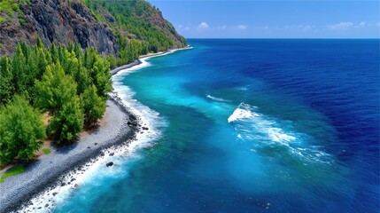 Obraz premium Steep Dark Rock Cliff Overhanging Deep Blue Ocean with Green Trees and Turquoise Water Near Rocky Shoreline Under Bright Sunlight