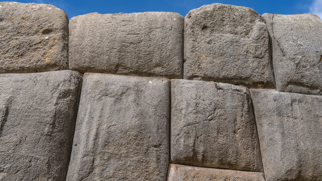 Ancient Ashlar polygonal masonry. A wall of Inca Fortress, huge boulders, hewn and tightly fitting to each other. Close-up. The blue sky. Peru. Sacsayhuaman 