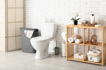 Stylish interior of light restroom with laundry basket