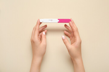Female hands with positive pregnancy test on color background