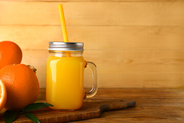 Mason jar of fresh orange juice on wooden background