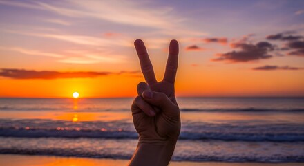 Peaceful Hand Showing Peace Sign at Sunset Beach with Vibrant Sky