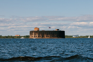 Historic round Fort Alexander I (Plague Fort) structure rising from the choppy water of the Gulf of Finland under a partly cloudy blue sky near Kronstadt