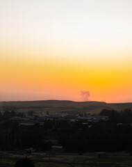 sunset background illuminating rural village and distant hills with warm gradient