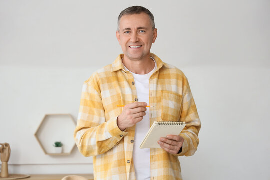 Mature man with notebook unpacking things in his new flat
