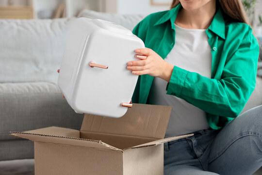 Young fashion blogger unpacking new cosmetic refrigerator at home, closeup