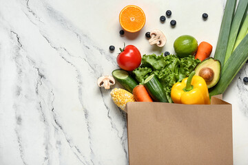 Shopping bag with different fresh vegetables and fruits on grunge white background. World Vegan Day