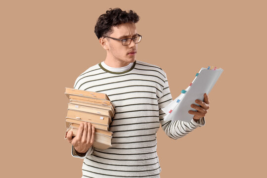 Male screenwriter with scenario and books on beige background