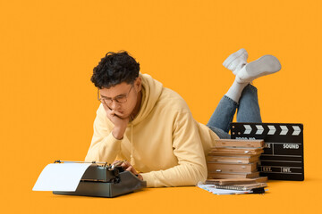 Thoughtful male screenwriter using typewriter on yellow background