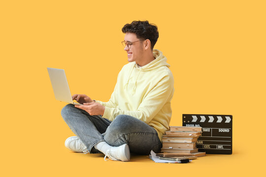 Male screenwriter with laptop writing script on yellow background