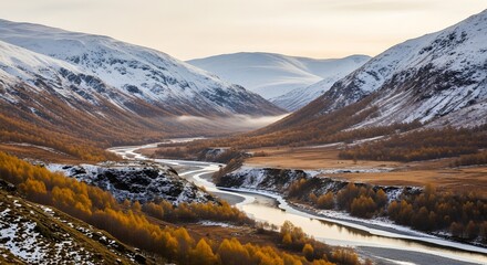 Winding river in a golden autumn valley framed by majestic snow-dusted mountains and a clear sky.