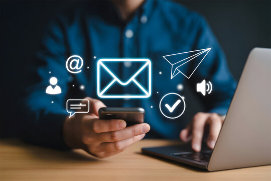 Businessman holding mobile phone with glowing email and communication icons - Powered by Adobe