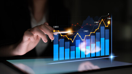 A businesswoman interacts with a digital tablet displaying dynamic market data visualizations, showcasing trends and analysis in a modern office setting. Scalp