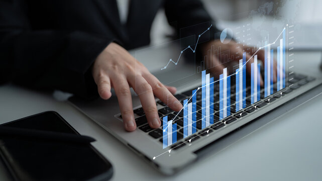 A focused business analyst inputs data on a laptop, showcasing transparent graphs and visualizations that reflect financial growth and market trends in a modern office space. Scalp