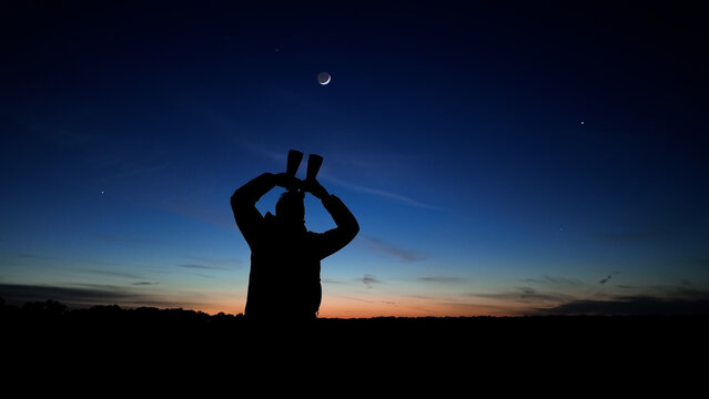 Amateur astronomer using binoculars for observing stars, planets, Moon and other celestial objects.