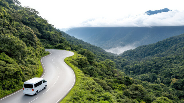 Winding mountain pass road with white van and lush green forest, misty valley mood
