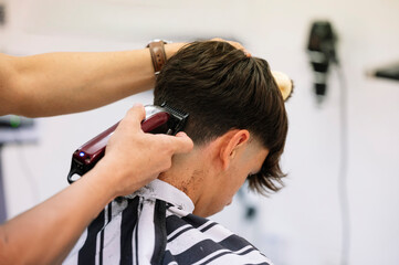 Fototapeta premium Barber finishing fade haircut on young man.