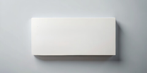 A plain white rectangle rests on a smooth gray surface, showcasing a minimalist design. The focus is on its simplicity and the strong contrast of colors, evoking calmness