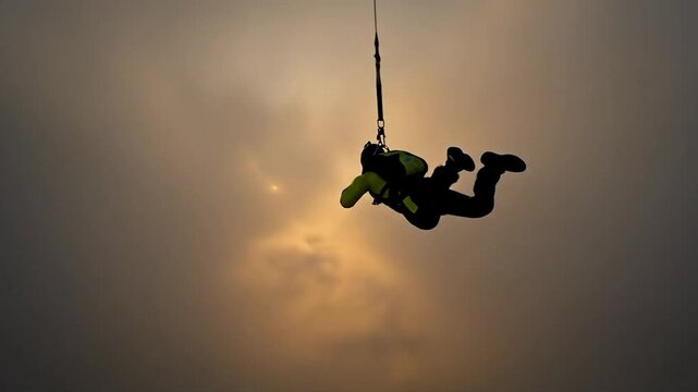 Skydiver freefalling above a sea of clouds at sunset, silhouetted against the sun
