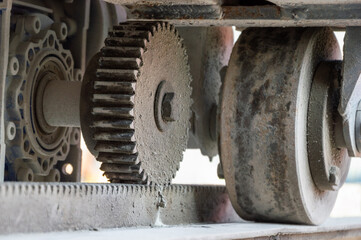 Close-up view of a complex gear system in an industrial machine, demonstrating wear and dust accumulation