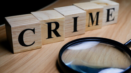 Crime investigation concept with magnifying glass and wooden blocks.