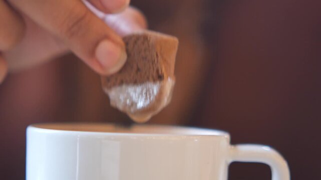 Enjoying a biscuit dipped in hot drink at cozy setting