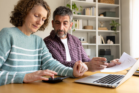 Mature couple managing home budget, planning finances using calculator