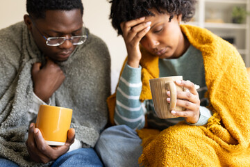 Sick couple suffering from cold or flu drinking hot tea on sofa