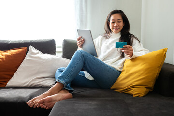 Woman online shopping using tablet and credit card at home