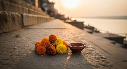Marigold flowers and clay lamp on riverbank steps at sunrise