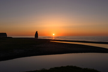 Sunrise casts silhouettes over calm Russian coastline waters