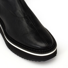 Détail Botte en cuir noir à la mode sur fond blanc