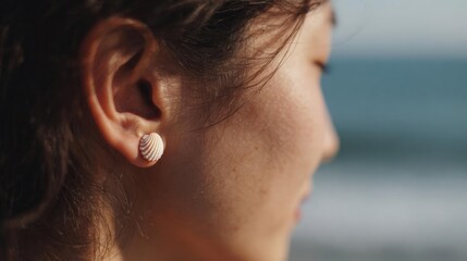 Close-up of a woman's ear. she is facing away from the camera, with her hair pulled back in a ponytail.