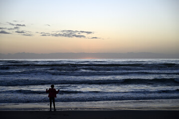 Naklejka premium Teens playing at italian beach. Some teens are playing at Viareggio beach during sundown. Some teens are playing with their mobile phone. Some teens are dancing.
