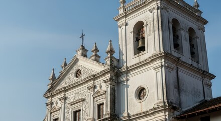 Fototapeta premium Historic white colonial church tower with bells against blue sky
