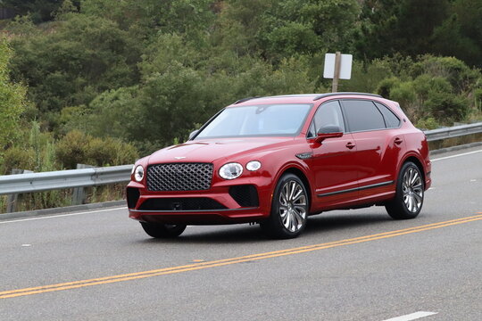 Red bentley bentayga suv driving on the road