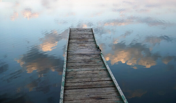 Bridge to the Clouds. Wooden village bridges over a lake reflecting the clouds.