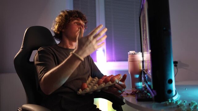 Young man throws an egg at the monitor in a burst of frustration neon light fills the room as emotions peak creating a chaotic messy moment where anger turns into impulsive action and sudden reaction